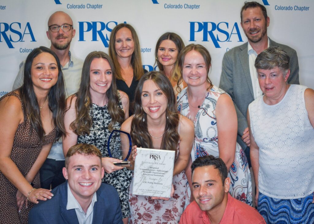Group of 11 CIG employees holding two campaign award trophies in front of a PRSA backdrop.